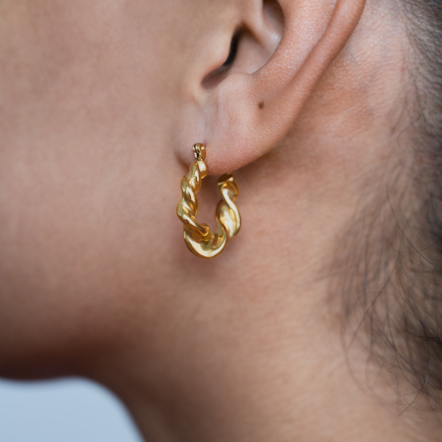 Chunky Twisted Hoop Earrings Non Tarnish shown worn in a model's ear