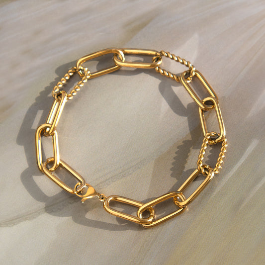 Gold chain bracelet on a light wooden surface