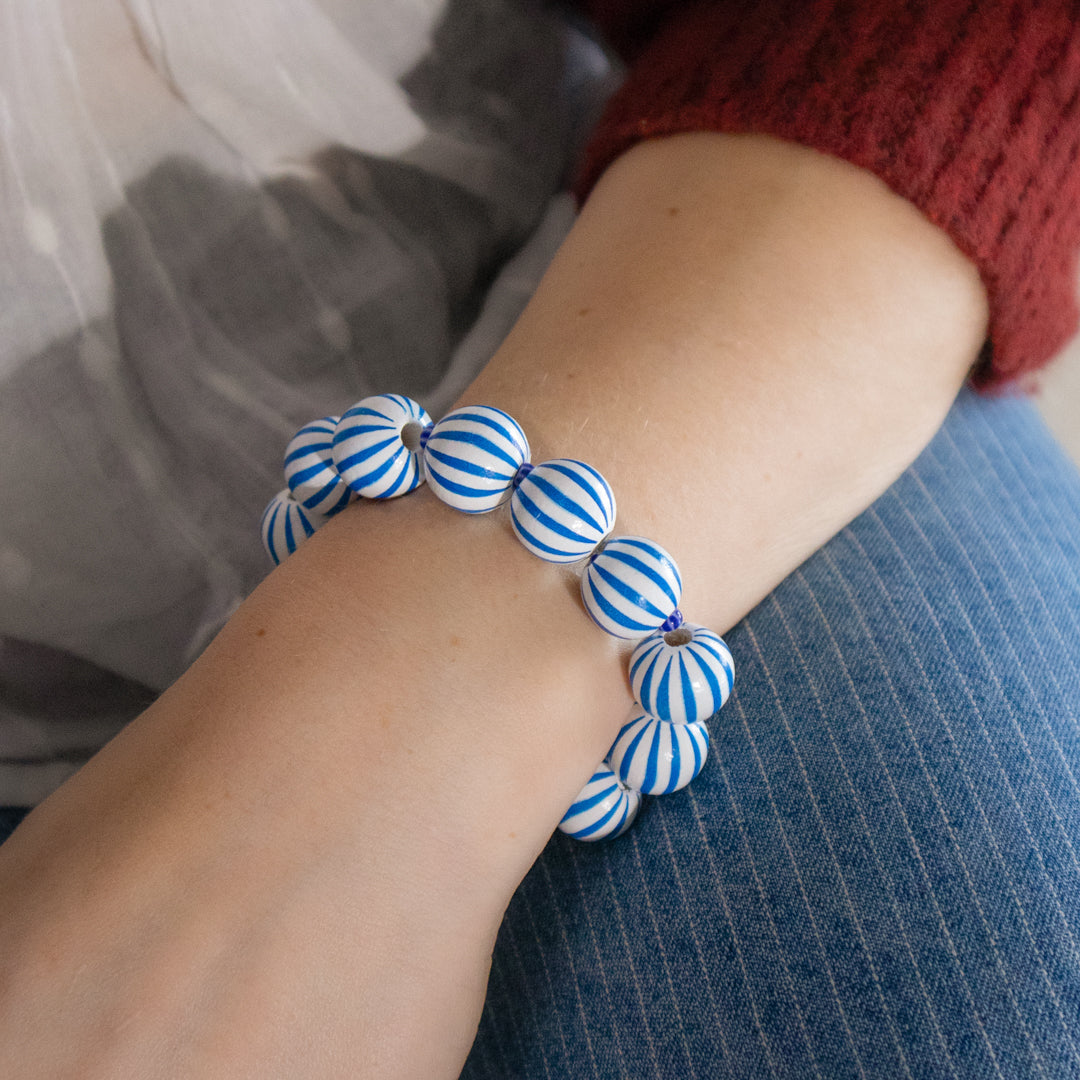 Blue and white striped bracelet on a wrist with a blurred background
