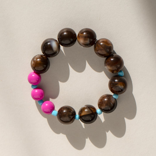 Beaded bracelet with brown beads and pink and blue accents on a beige background