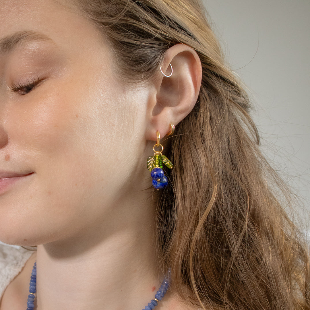 Close-up of a woman wearing colorful earrings with a neutral background