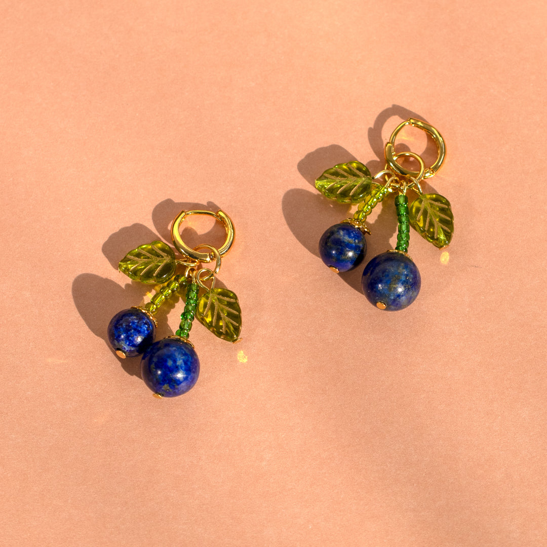 Blue cherry and green leaves earrings on pink background