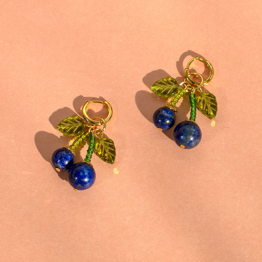 Blue cherry and green leaves earrings on pink background