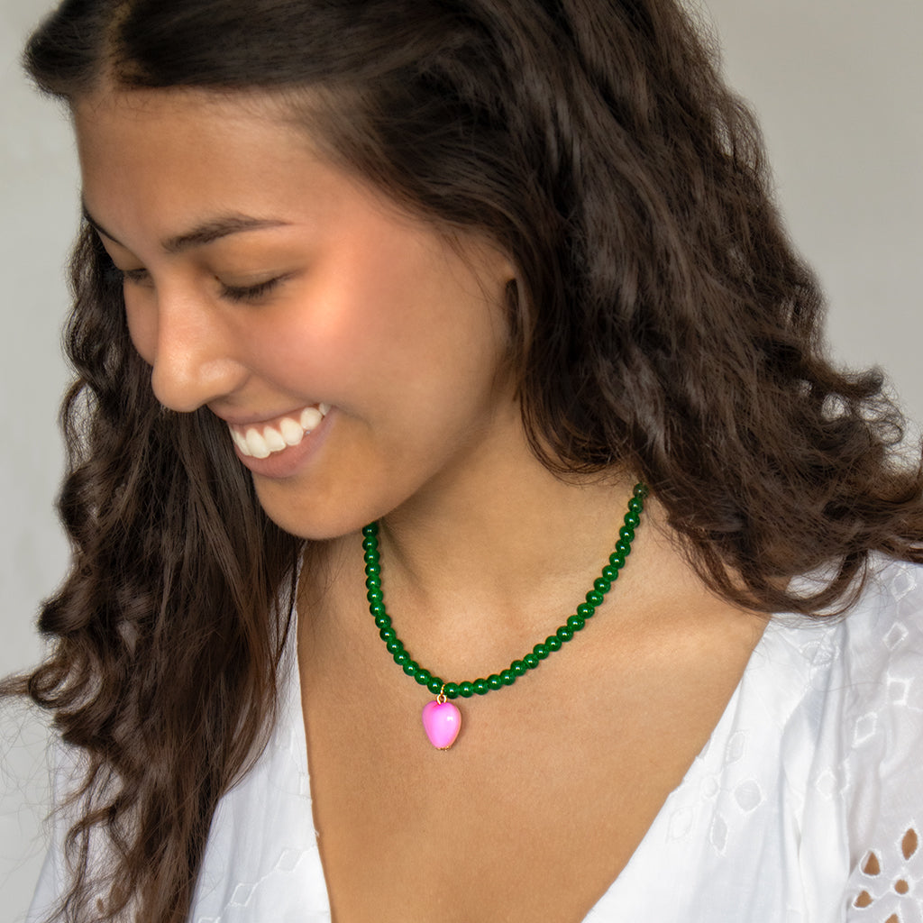 Model wearing green bead and pink heart necklace