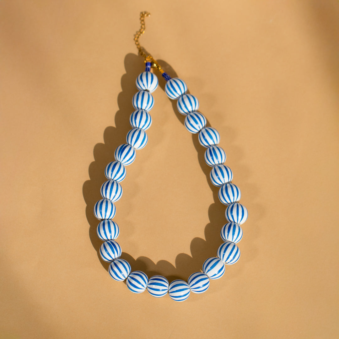 Blue and white striped necklace on a beige background