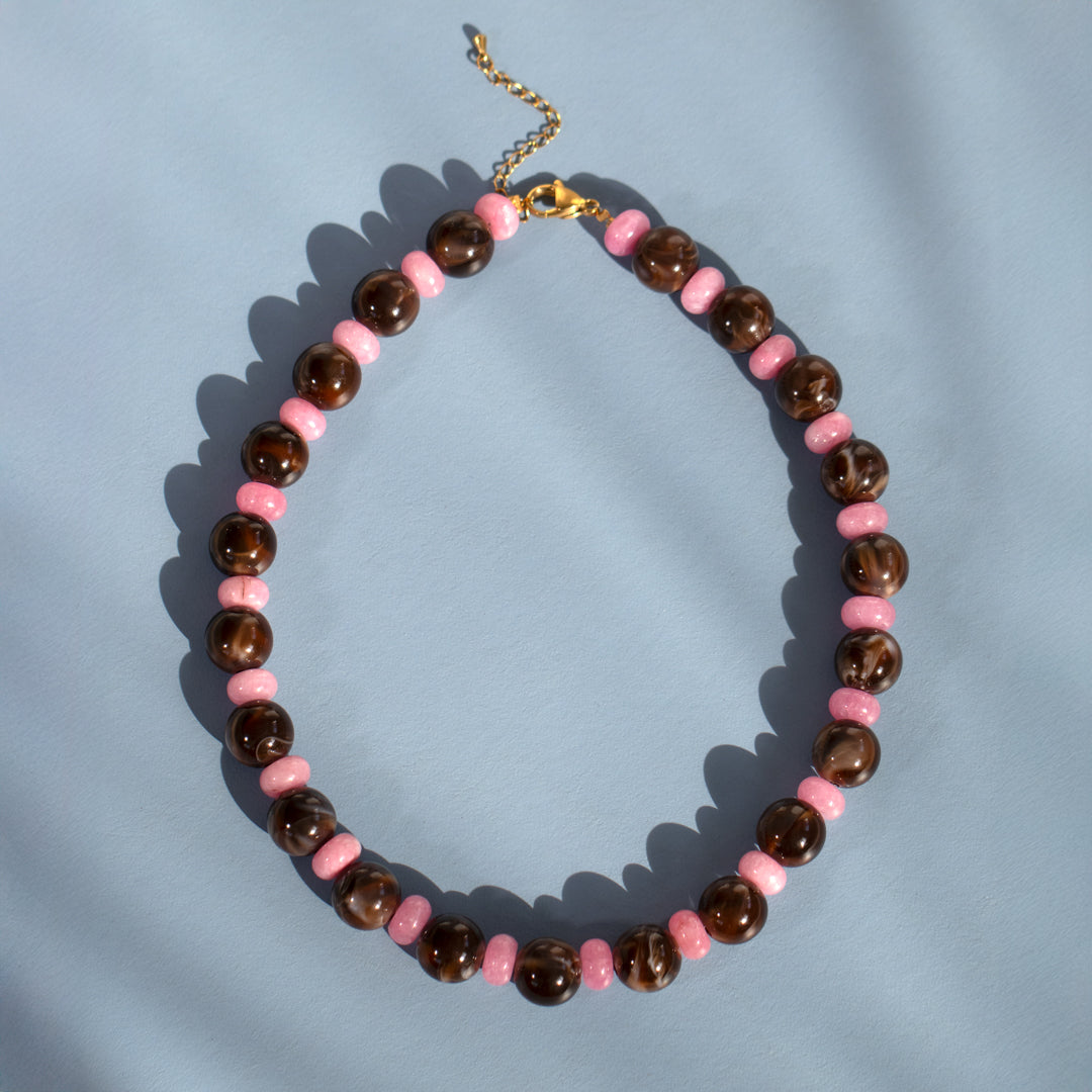 Necklace with pink and brown beads on a light blue background