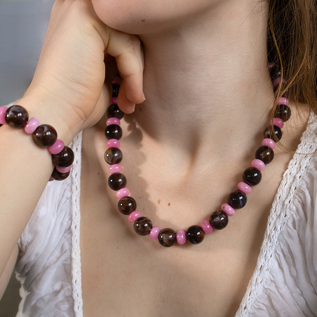 Person wearing a pink and brown beaded necklace with matching bracelet.