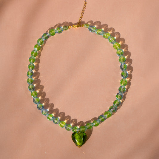 Iridescent Olive Heart Bead Necklace against pink background