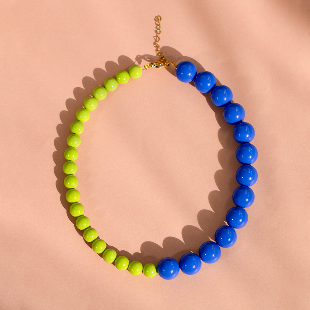 Necklace with green and blue beads on a pink background
