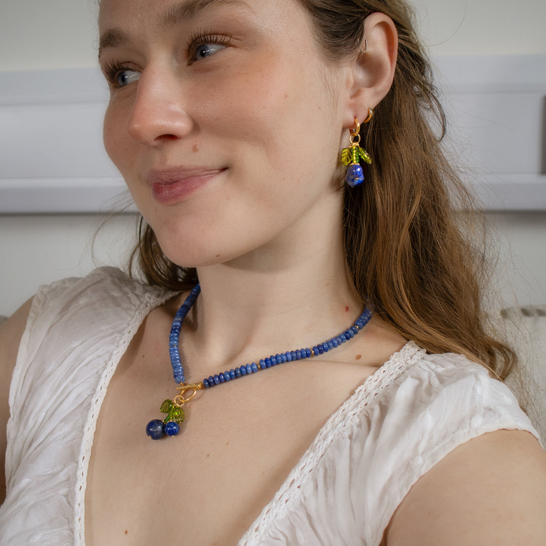 Woman wearing a blue beaded necklace and earrings indoors
