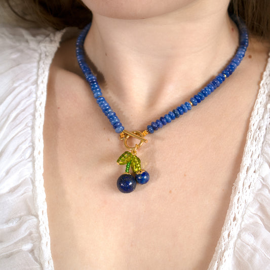 Necklace with blue beads and cherry charm worn by a person